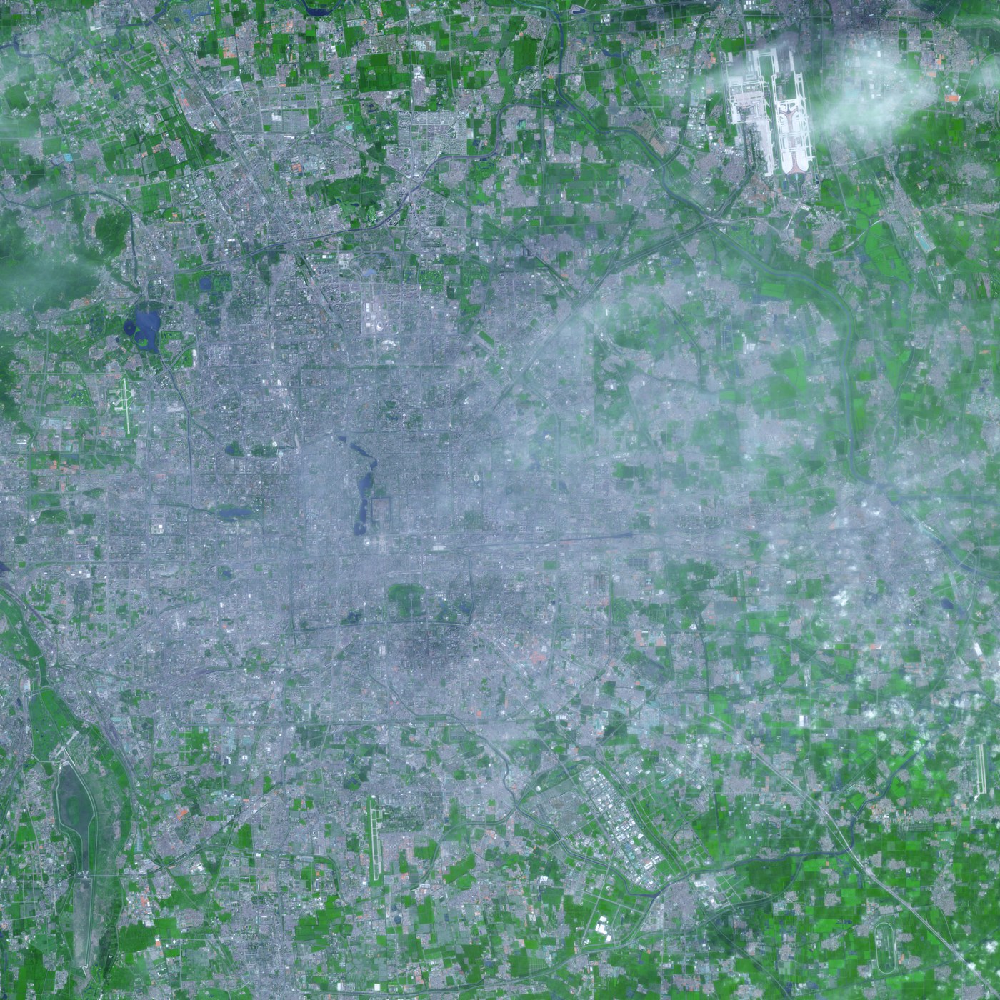 Vue satellite de Pékin, en Chine, montrant l’étendue grise de la ville et les terres végétalisées qui l’entourent.