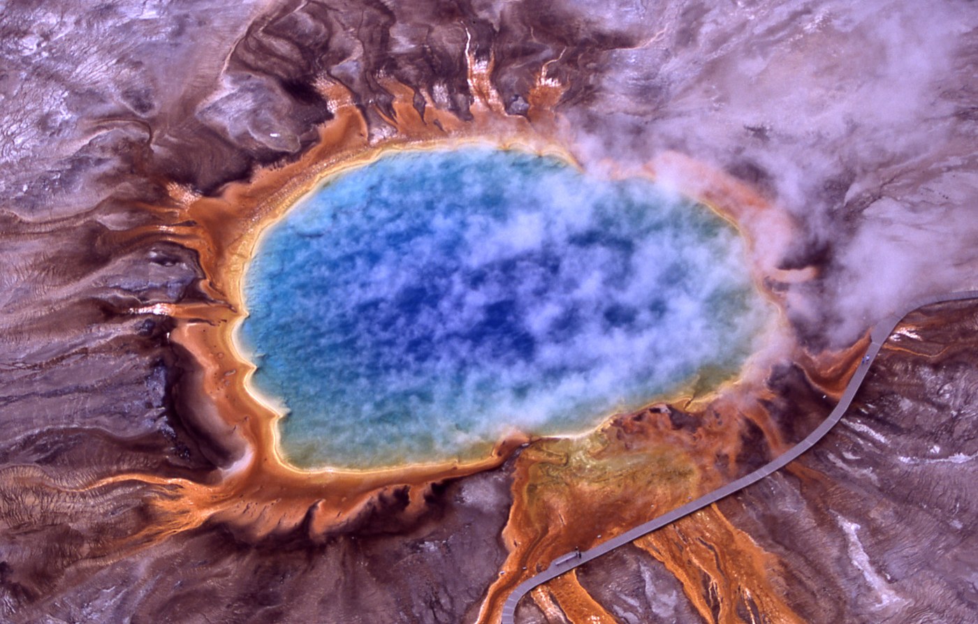 Vue aérienne de Grand Prismatic Spring à Yellowstone, aux États-Unis, avec son bassin bleu, ses bordures orange et la vapeur qui s’en dégage.